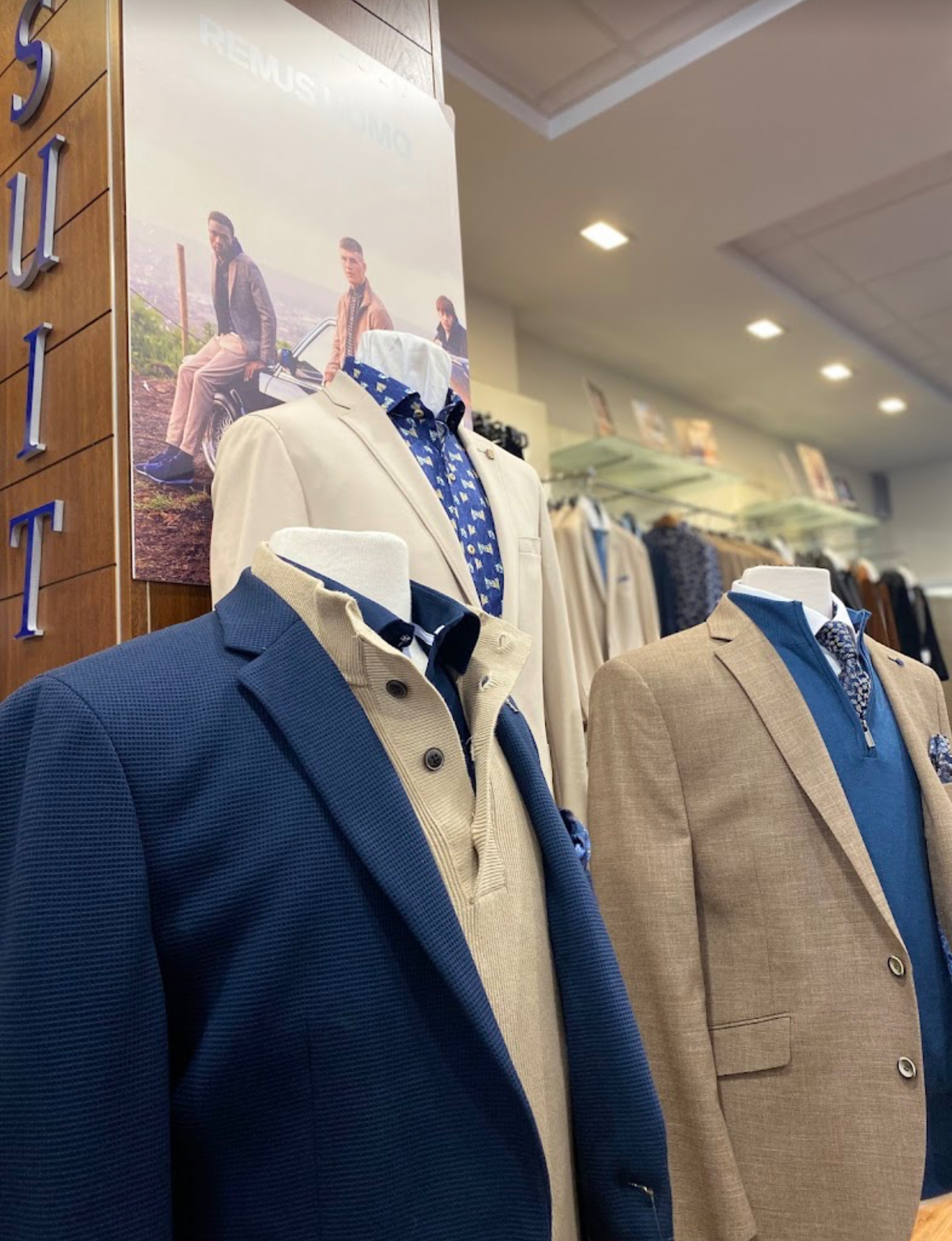 Tailored jackets and shirts styled on mannequins beside the suit rails